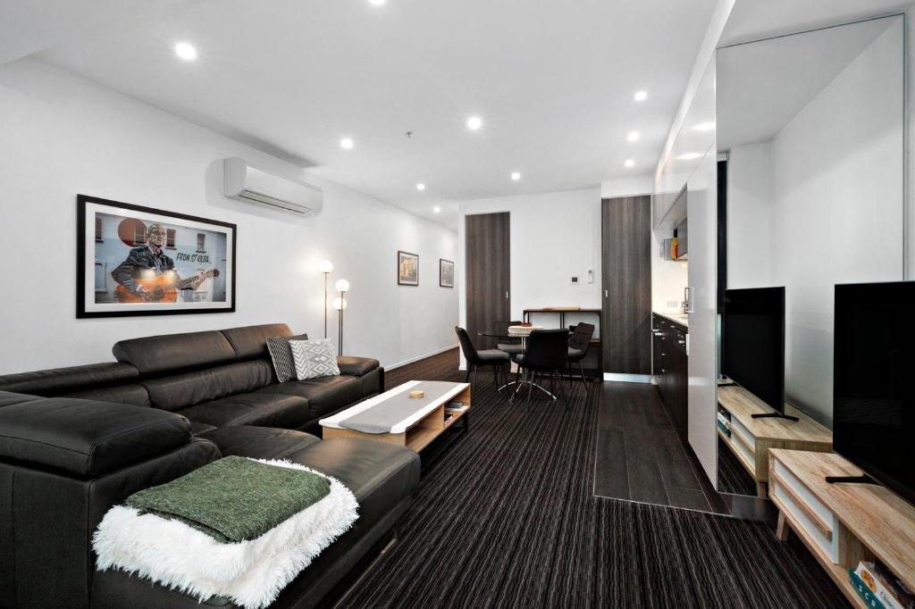 a living room with a black couch and a table at A tale awaits - just steps from trendy cafés and lively bars in Melbourne