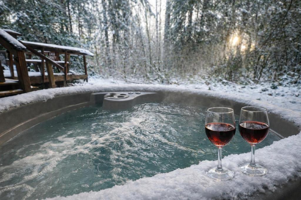 two glasses of wine sitting next to a hot tub at Serenity A Frame in Ashford