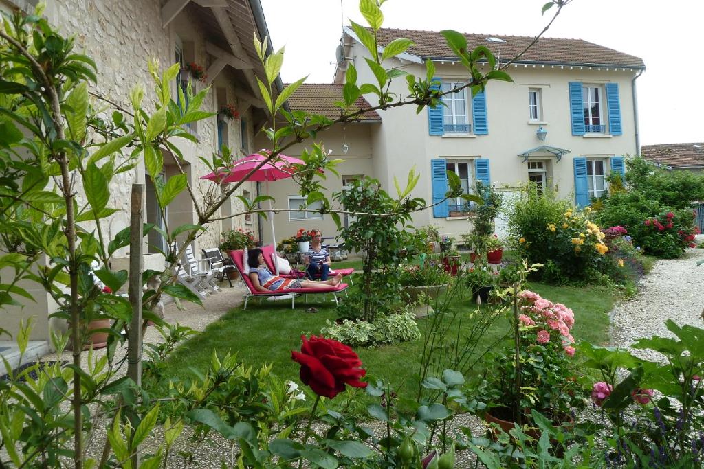 a garden in front of a house with flowers at Les chambres d'hôtes Joy in Val de Vesle