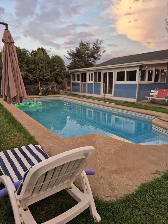 a chair and an umbrella next to a swimming pool at Casa Montes Valle Alegre in Quintero
