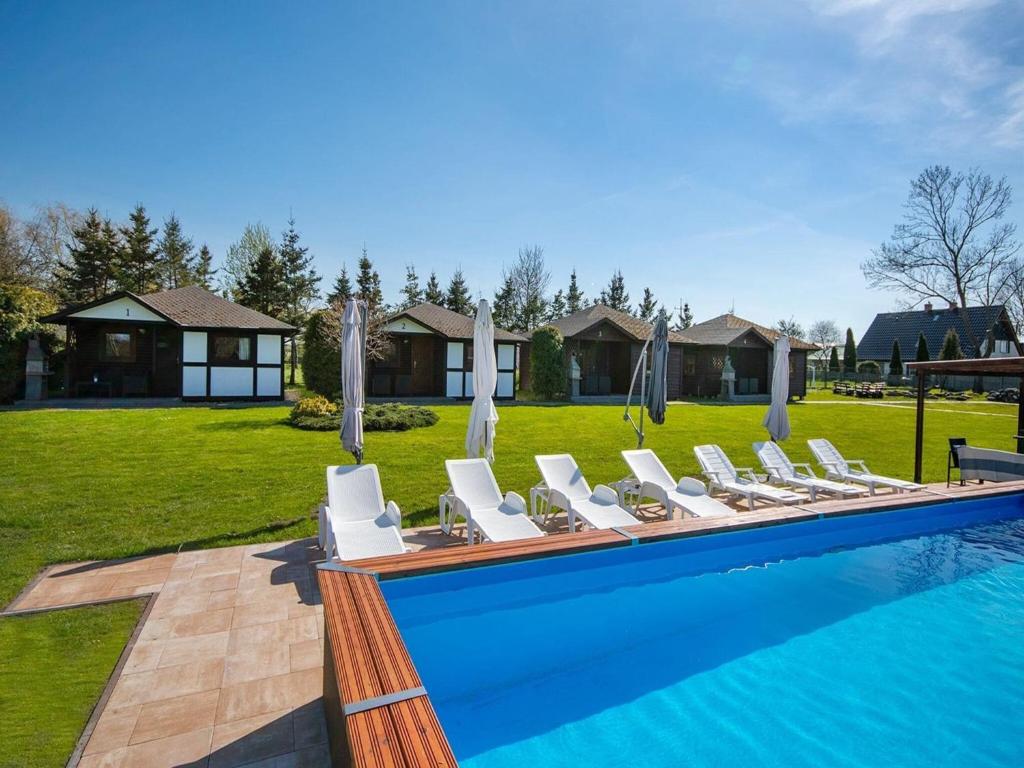 a row of white chairs sitting next to a swimming pool at Comfortable holiday homes, jacuzzi, summer pool in Łacko