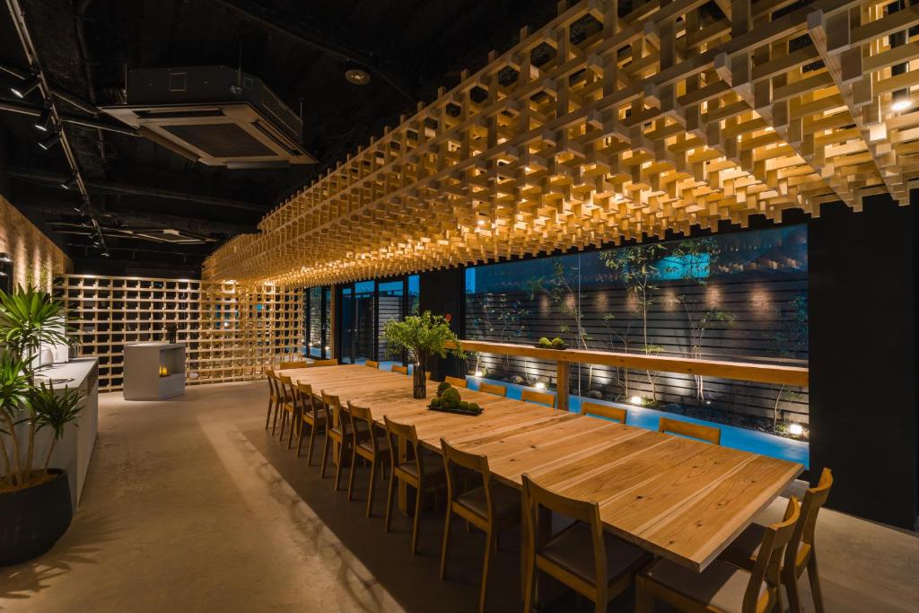 a long table in a room with chairs and lights at BAKURO - Doyanen Hotels in Osaka
