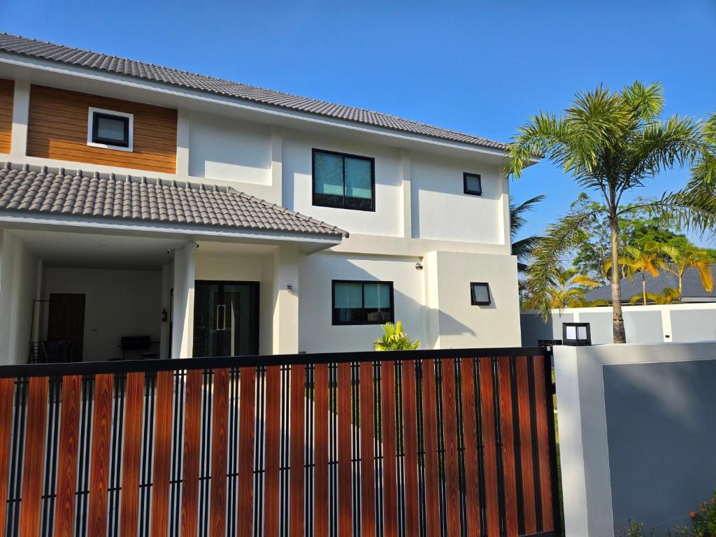 a white house with a fence and palm trees at Vanesa Serenity Villa 1 in Ban Chong Phli