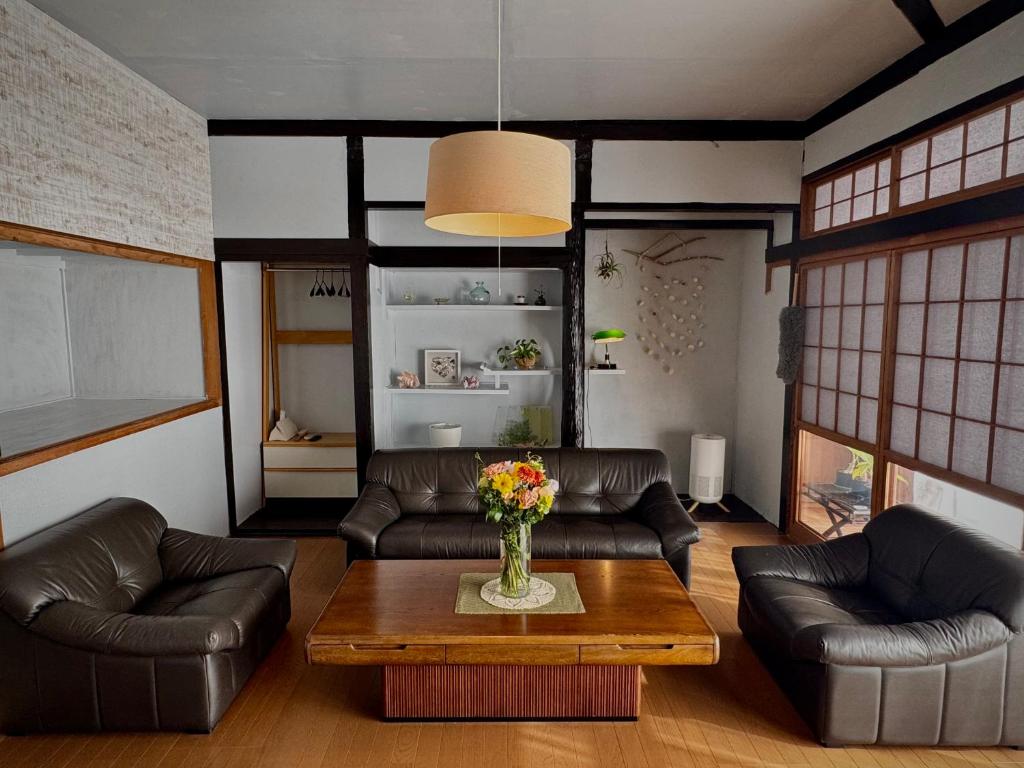 a living room with leather couches and a coffee table at 愛犬と泊まれる宿 ほこほこsaza 一棟貸し 海も川も徒歩圏内 dog run付き 釣りの穴場 サーフィン 自然 満点星空 蛍鑑賞 最大7名 in Miyazaki
