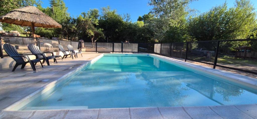 a swimming pool with chairs and an umbrella at Casa Playa Mansa in Mina Clavero