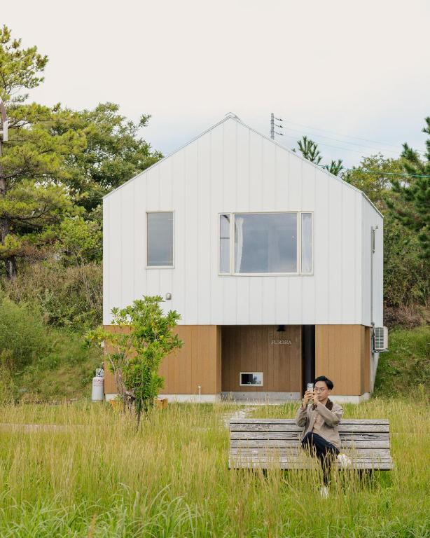 a woman sitting on a bench in front of a house at furaha in Iwamicho