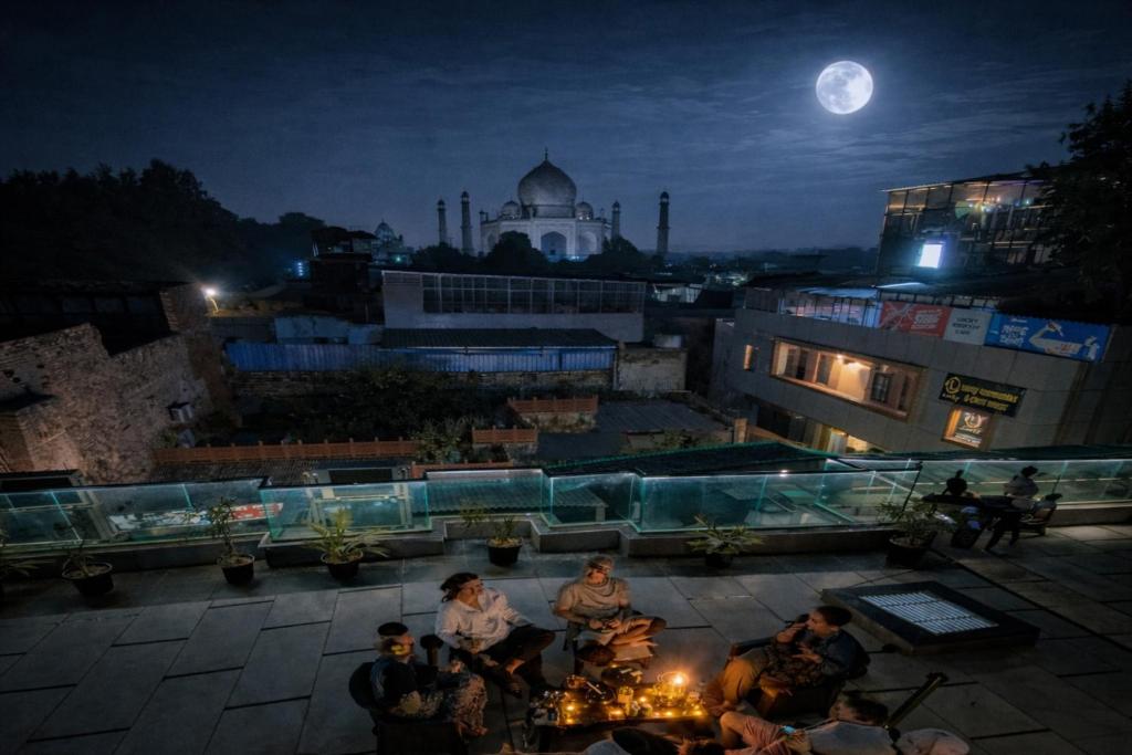 a group of people sitting on a rooftop at night at The Vacation Villa Agra A Boutique Hotel Near Taj Mahal in Agra