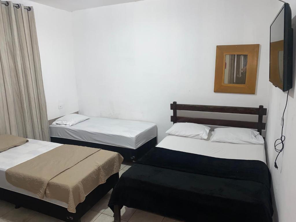 a bedroom with two beds and a mirror at Hotel Classic in Porangatu
