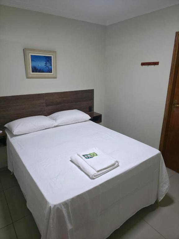a white bed with two white towels on it at Pousada Alvorada in Engenheiro Coelho