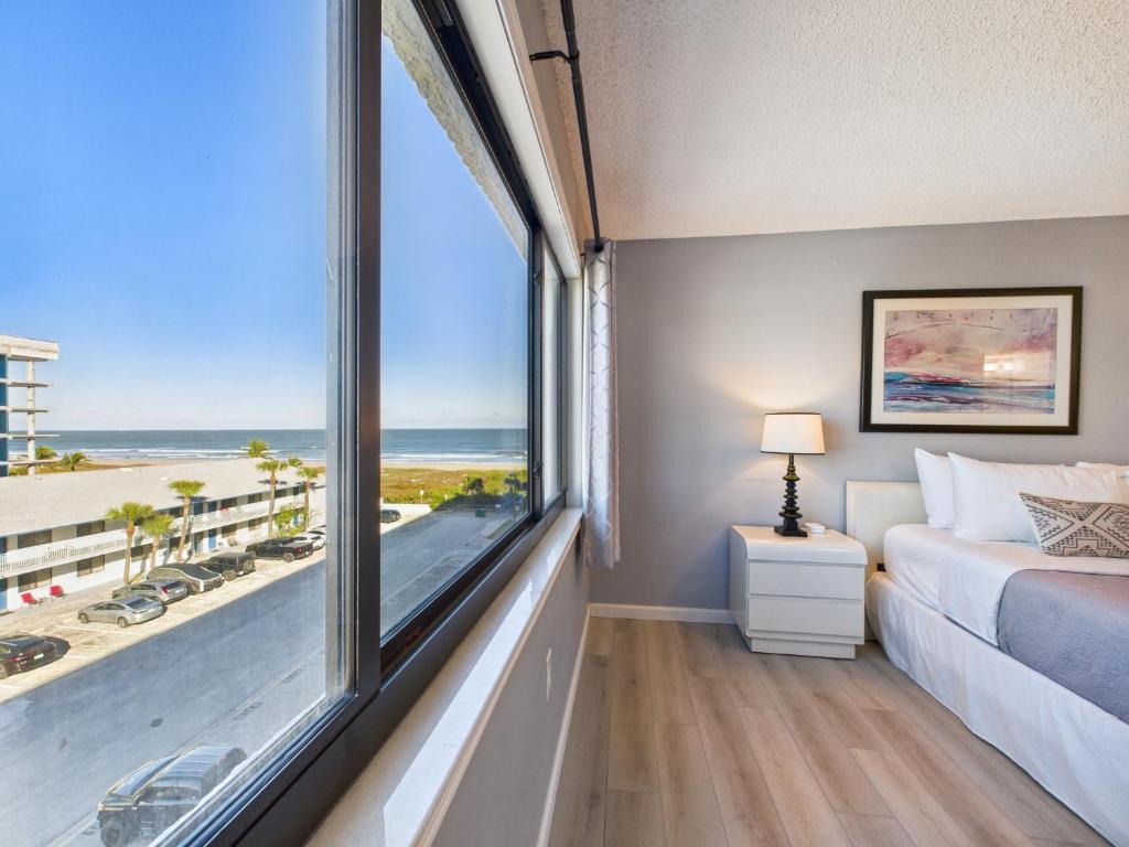 a bedroom with a large window with a view of the beach at Sandcastles 2BR2BA Cocoa Beach Ocean Views! in Cocoa Beach