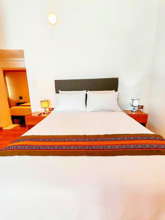 a large white bed in a room with two tables at Cusco - Flor de Loto in Cusco