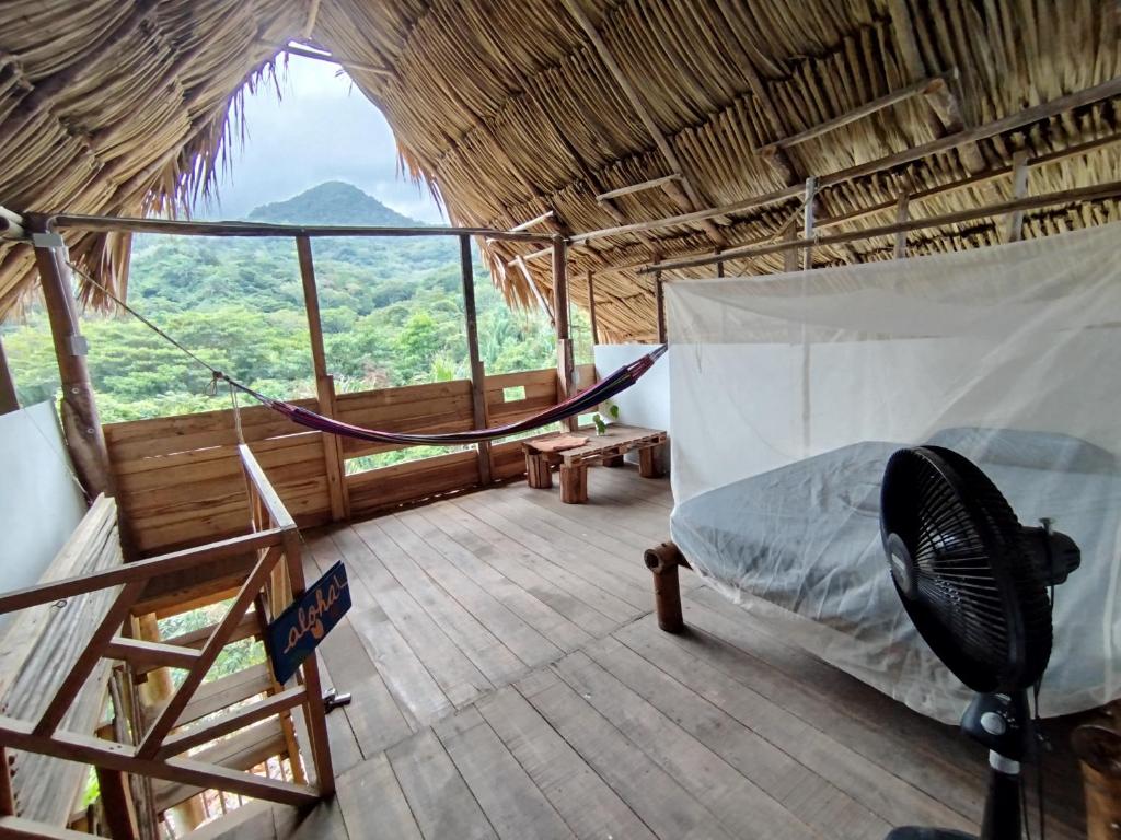 a room with a bed and a hammock in a hut at Siwi Lodge in Cañaveral