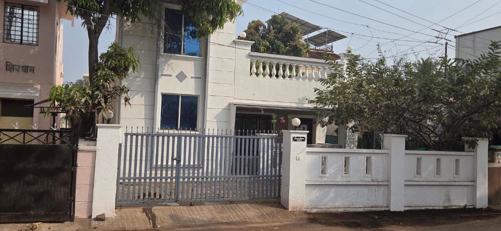 a white fence in front of a white house at Sunshinee Villa in Pune