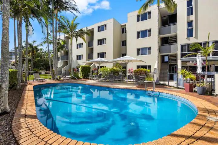 a large blue swimming pool in front of a building at Joanne Apartments in Caloundra