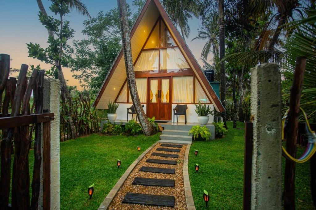 a house with a triangular roof with a pathway leading to it at River Bend Nook in Ahangama