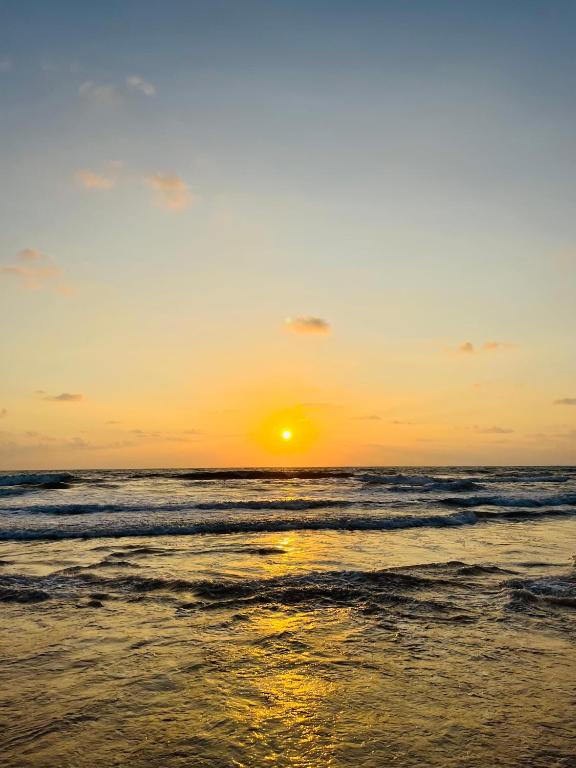 a sunset on a beach with the ocean at Zandeepa Homestay in Ahungalla