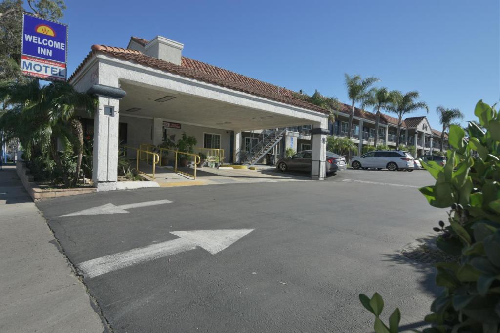 a parking lot with an arrow sign in front of a building at Welcome Inn Corona in Corona
