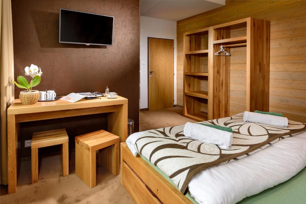 a bedroom with a bed with a desk and a tv at Vila Emma in Vysoke Tatry - Strbske Pleso
