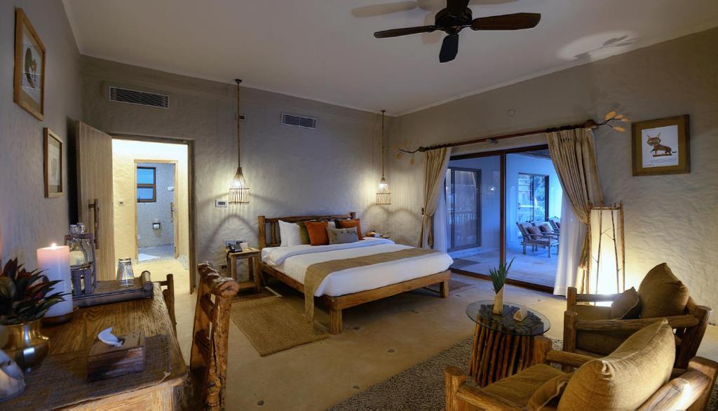 Un dormitorio con una cama y una sala de estar. en Barahi Jungle Lodge, en Meghauli