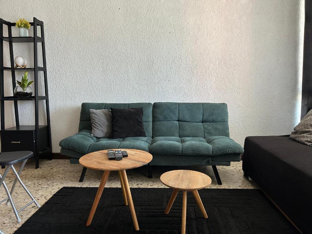 a living room with a green couch and two tables at Comfortable apartment 10 min BBVA Stadium - Wi-fi Parking SmartTV & AC in Monterrey