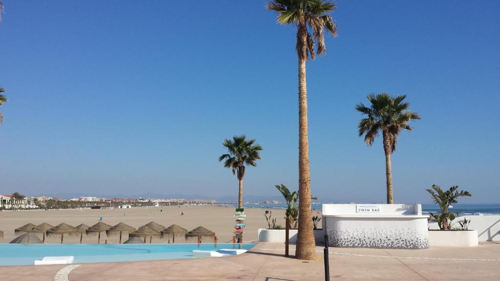 a swimming pool with palm trees and a beach at Apartment on Carrer del Dr. Lluch in Valencia