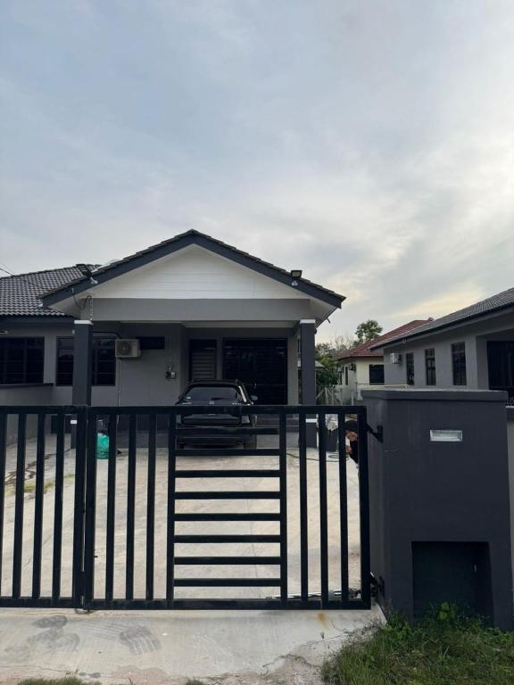 a house with a gate and a car in front of it at Student Homestay in Kampong Ru Sepuloh