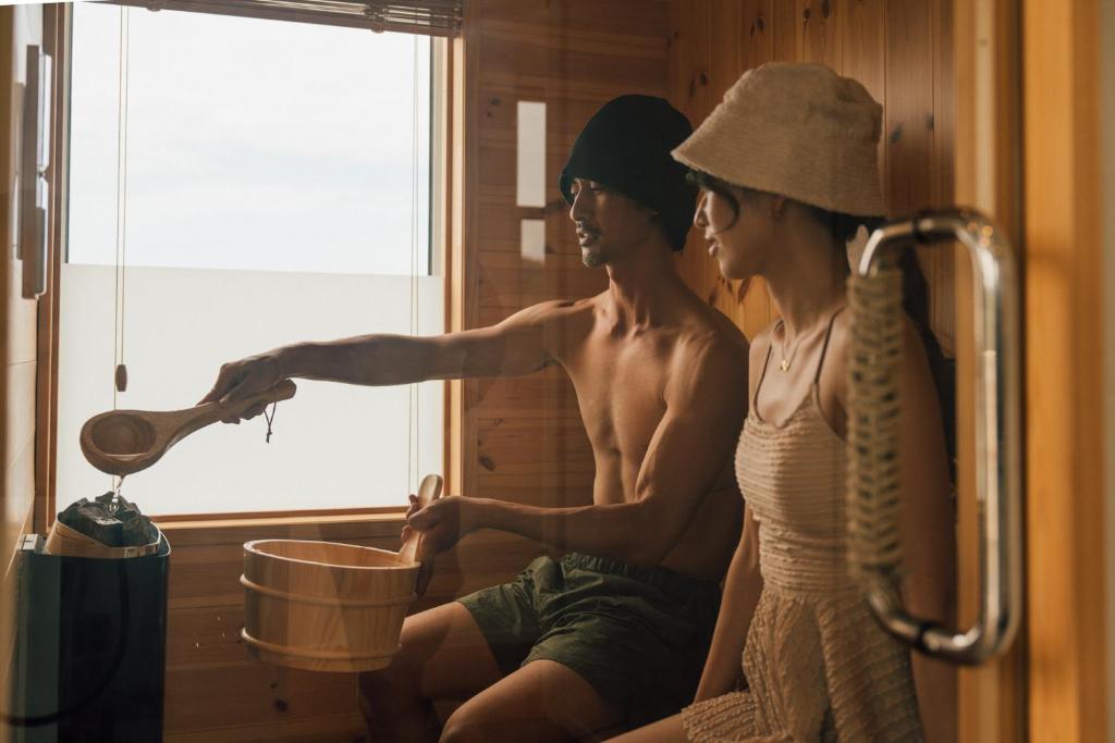 a man and a woman sitting in a room with a bucket at Villala Fibana in Motobu