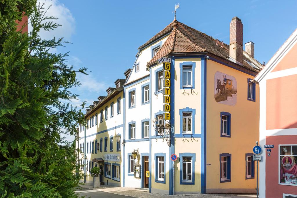 ein weißes Gebäude mit einem gelben Schild darauf in der Unterkunft Hotel-Gasthof Zur Post in Velburg