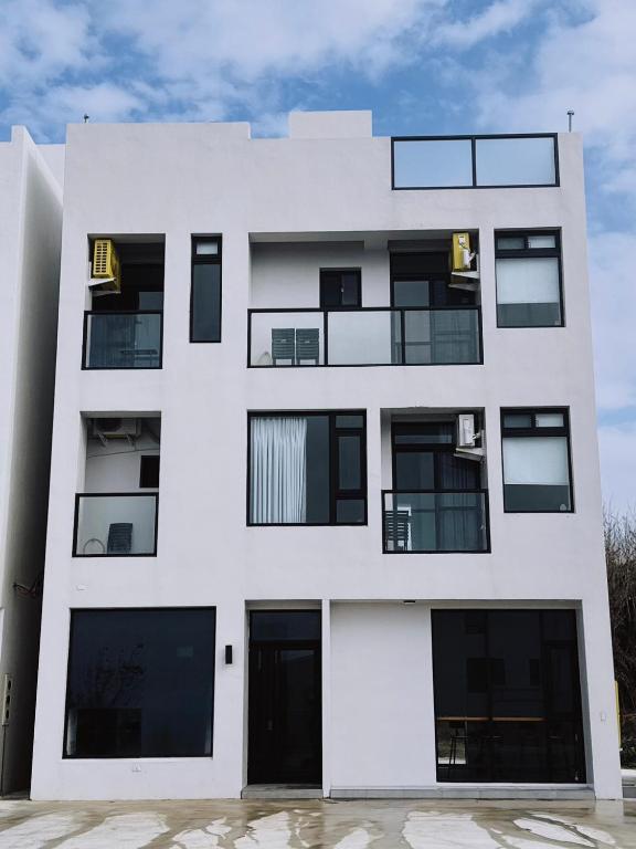 a white building with black windows at IsShoNi B&B in Huxi