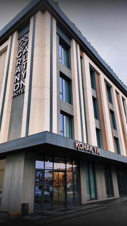 a building with a sign on the front of it at Grand Altyn Hotel in Shymkent