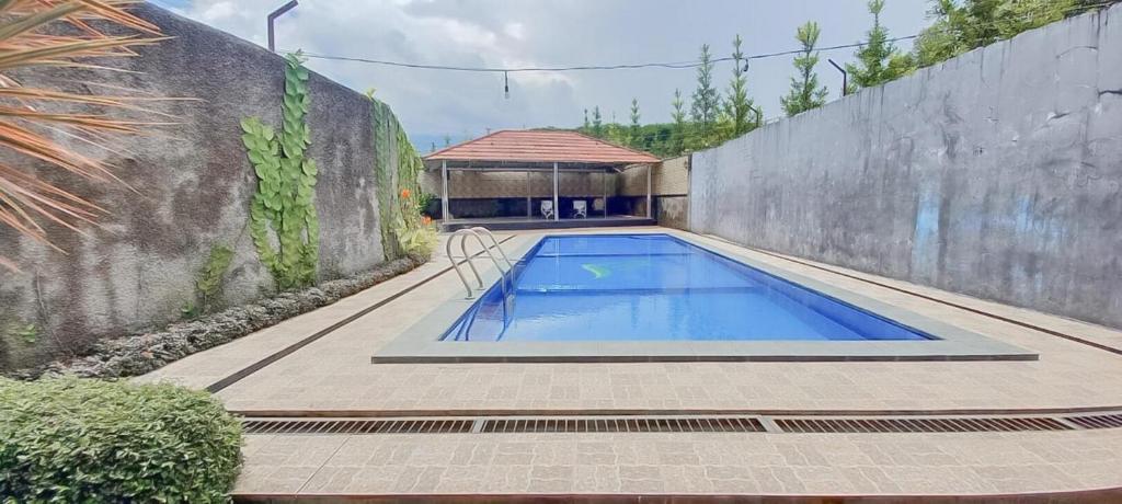 a swimming pool in a yard next to a wall at Hotel Sri Indrawati Puncak Mitra RedDoorz in Bogor