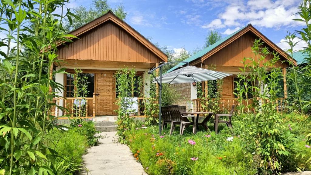 a wooden house with a table and an umbrella at Tololing Eco Resort in Suktiyāl