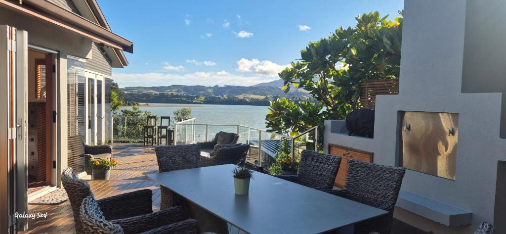 a table and chairs on a balcony with a view of the water at Luxurious Living + Spa - beautifully presented in Raglan