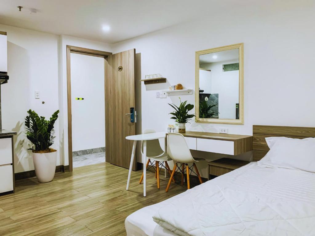 a bedroom with a bed and a desk and a kitchen at sentosa apartments in Dien Ban