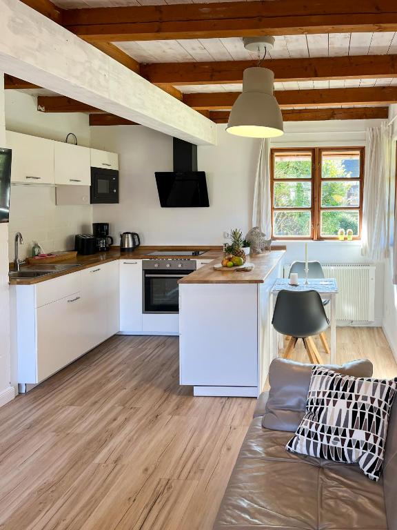 a kitchen and living room with white cabinets and a couch at Kleiner Anker in Fehmarn