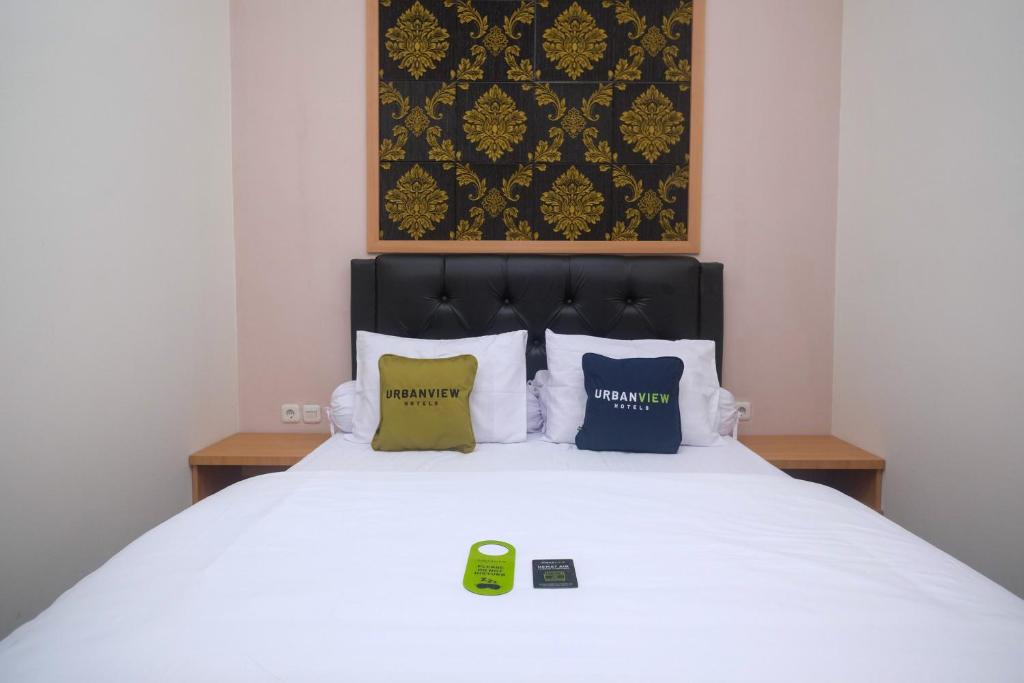a bedroom with a white bed with four pillows at Urbanview Grand Lotus Hotel by RedDoorz in Purwokerto