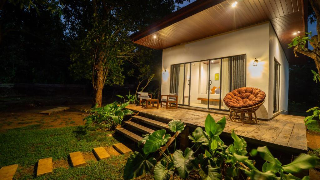 a small house with a wooden deck with a chair at Vilona Nature Villa in Dambulla