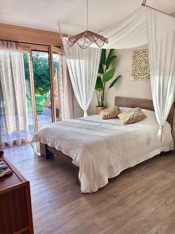 a bedroom with a large bed with white curtains at Lake View in Le Sentier