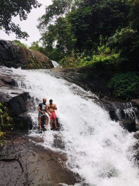 two people riding bikes in a waterfall at Pepper Valley Resort in Kalpetta