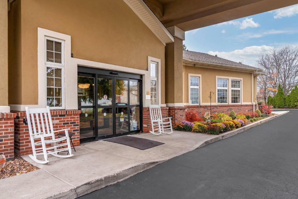 two white chairs sitting outside of a house at Comfort Inn University in Amherst