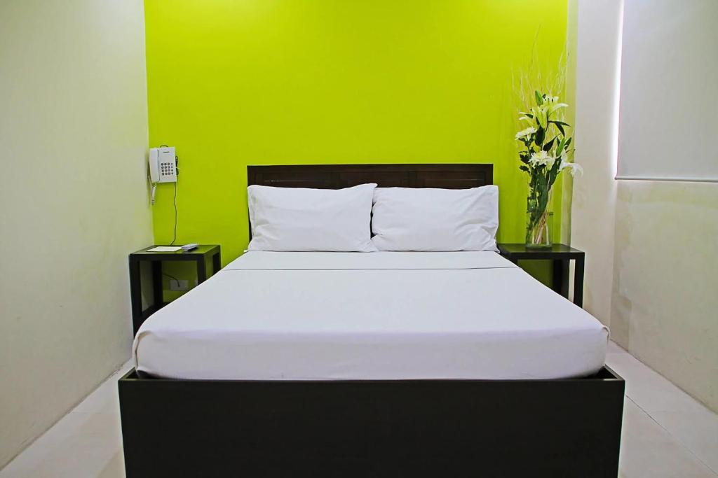 a bed in a room with a green wall at Rana Hotel in Sampong
