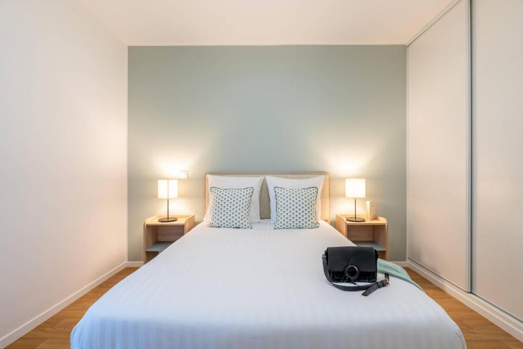 a bedroom with a large white bed with two lamps at Quality Aparthotel Nancy Zenith in Laxou