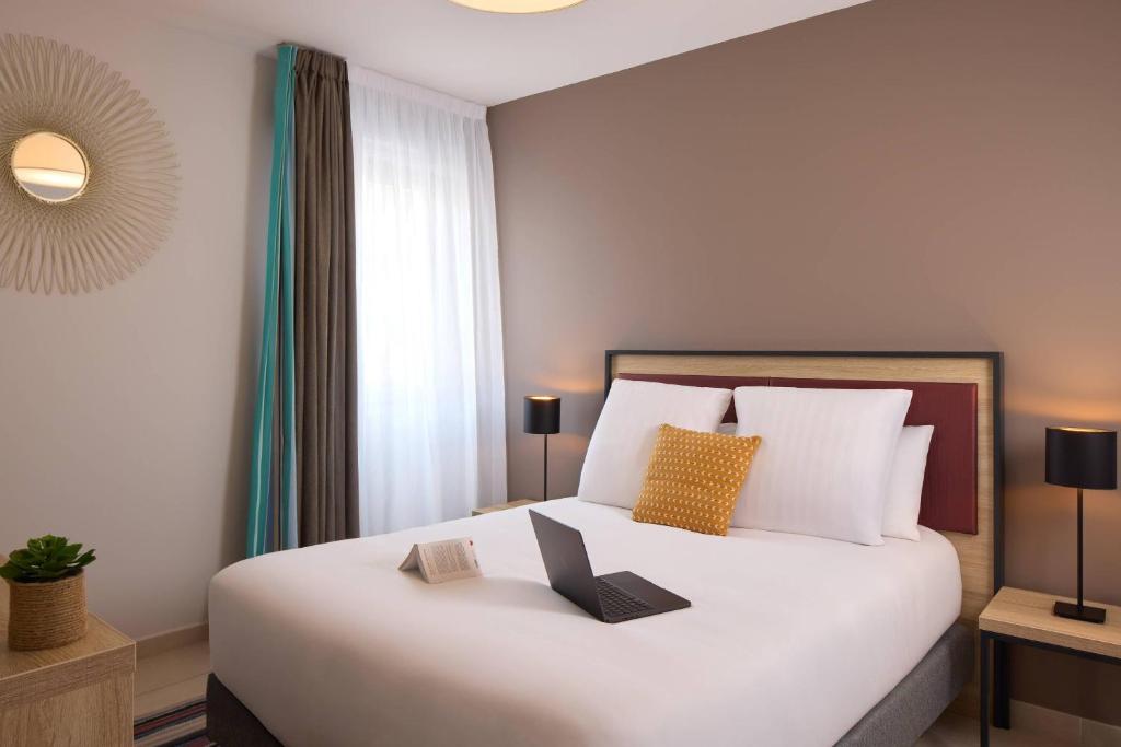 a bedroom with a bed with a laptop on it at Quality Aparthotel Perpignan Prestige in Perpignan