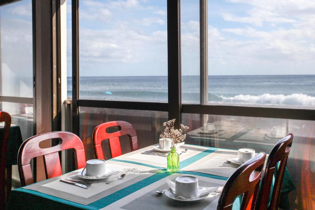 a table with chairs and a view of the ocean at Aparthotel Barracuda in Ponta Delgada