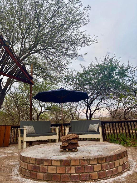 a fire pit with two chairs and an umbrella at Kudu's Corner in Marloth Park