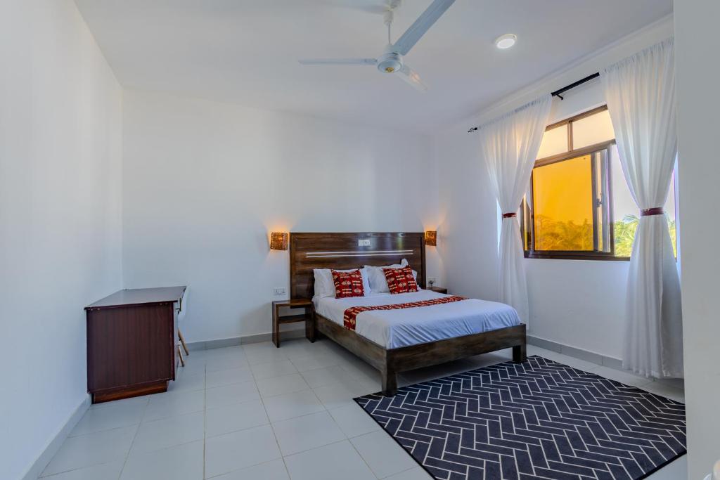 a bedroom with a bed and a desk and a window at Wendy's Da-Azizi Homes Diani in Diani Beach
