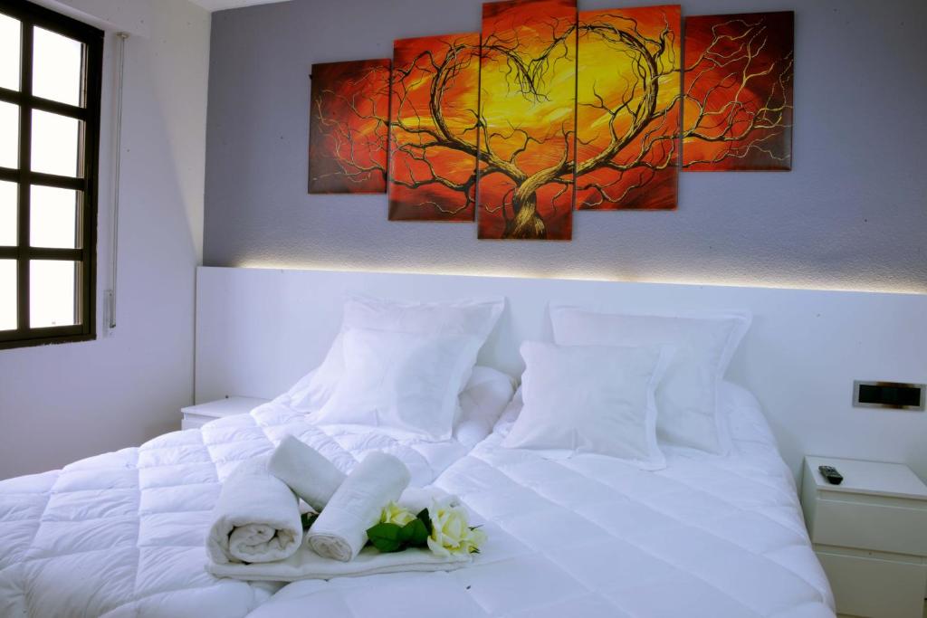 Una cama blanca con toallas y una pintura en la pared. en Hostal El Júcar, en Alcalá del Júcar