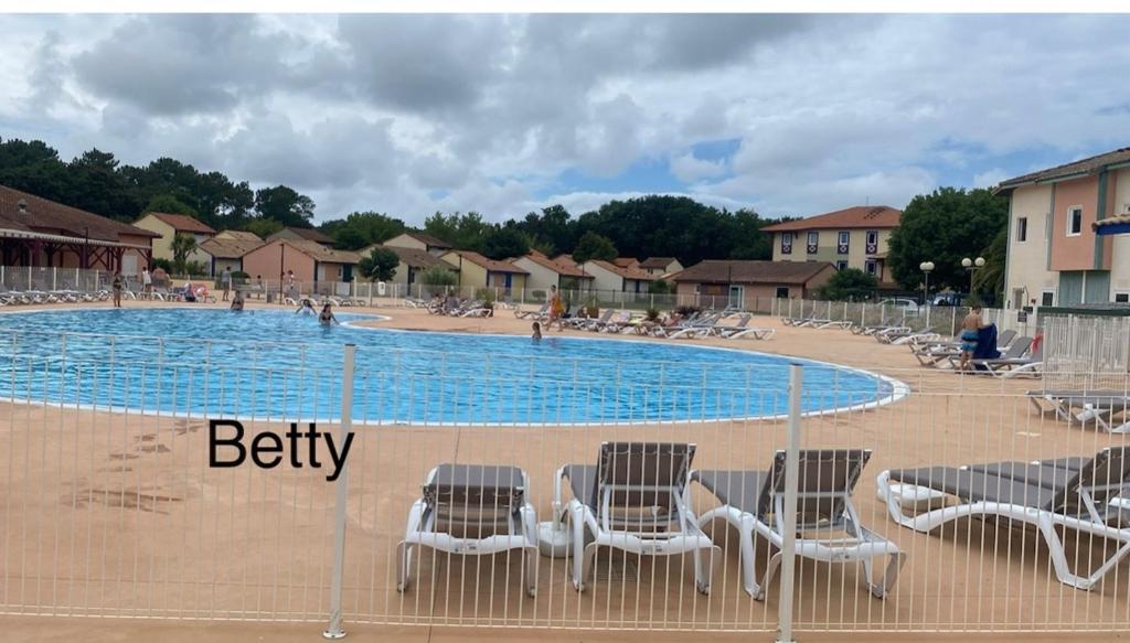 a group of chairs sitting next to a swimming pool at Appart pour 4 à 6 pers Les résidences du lac Soustons plage Piscine proche golf océan in Soustons