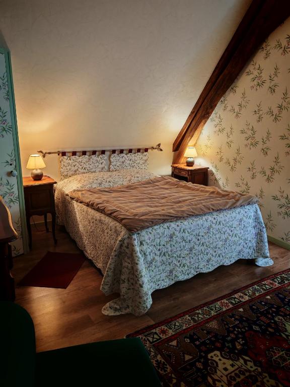 a bedroom with a bed and two lamps on two tables at Chambre d'hôte La Berthoderie in Morlac