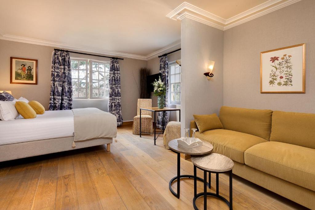 a hotel room with a bed and a couch at CAZAUDEHORE Hôtel Restaurant Gastronomique Terrasse et Jardins in Saint-Germain-en-Laye